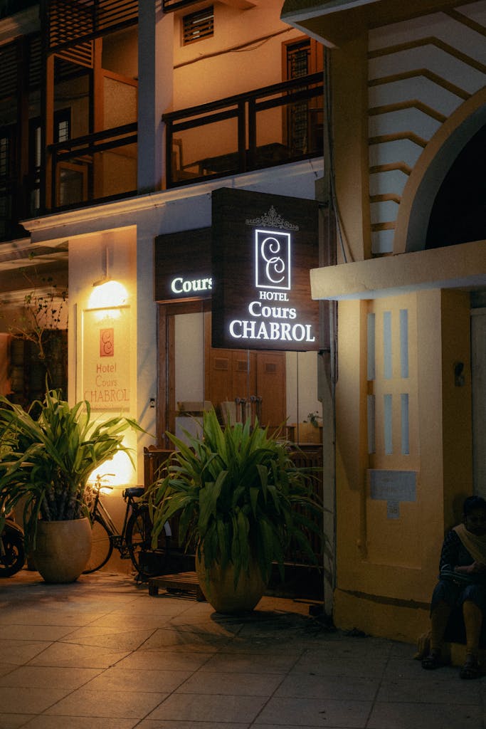 A nighttime street view showcasing the illuminated Hotel Cours Chabrol facade in Puducherry, India.